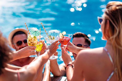 Friends relaxing with colourful drinks beside the water