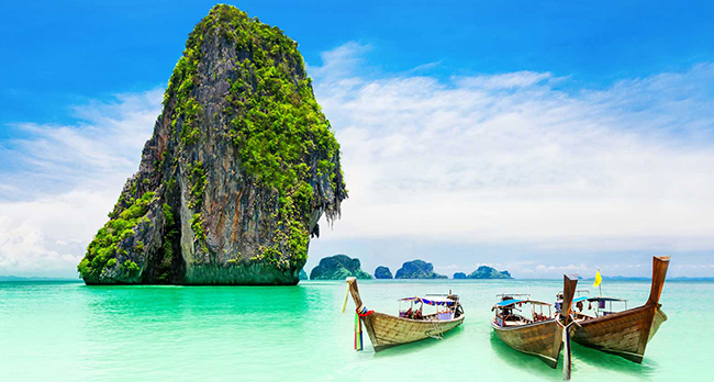 Limestone islands and long-tail boats on turquoise water in Thailand